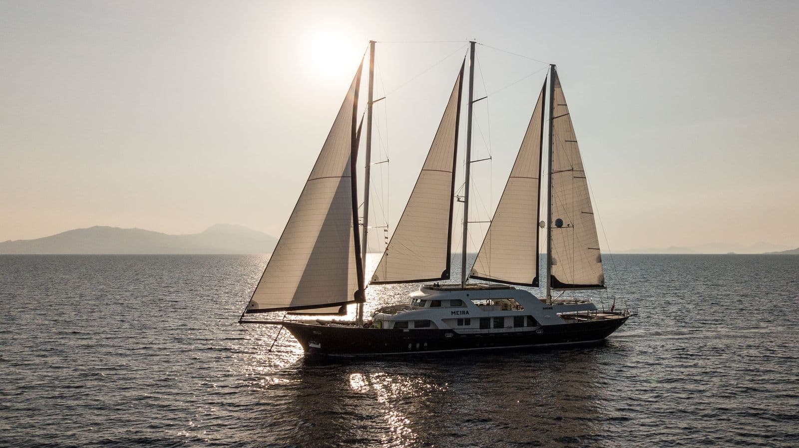 M/S MEIRA under sail, backlit at sunset