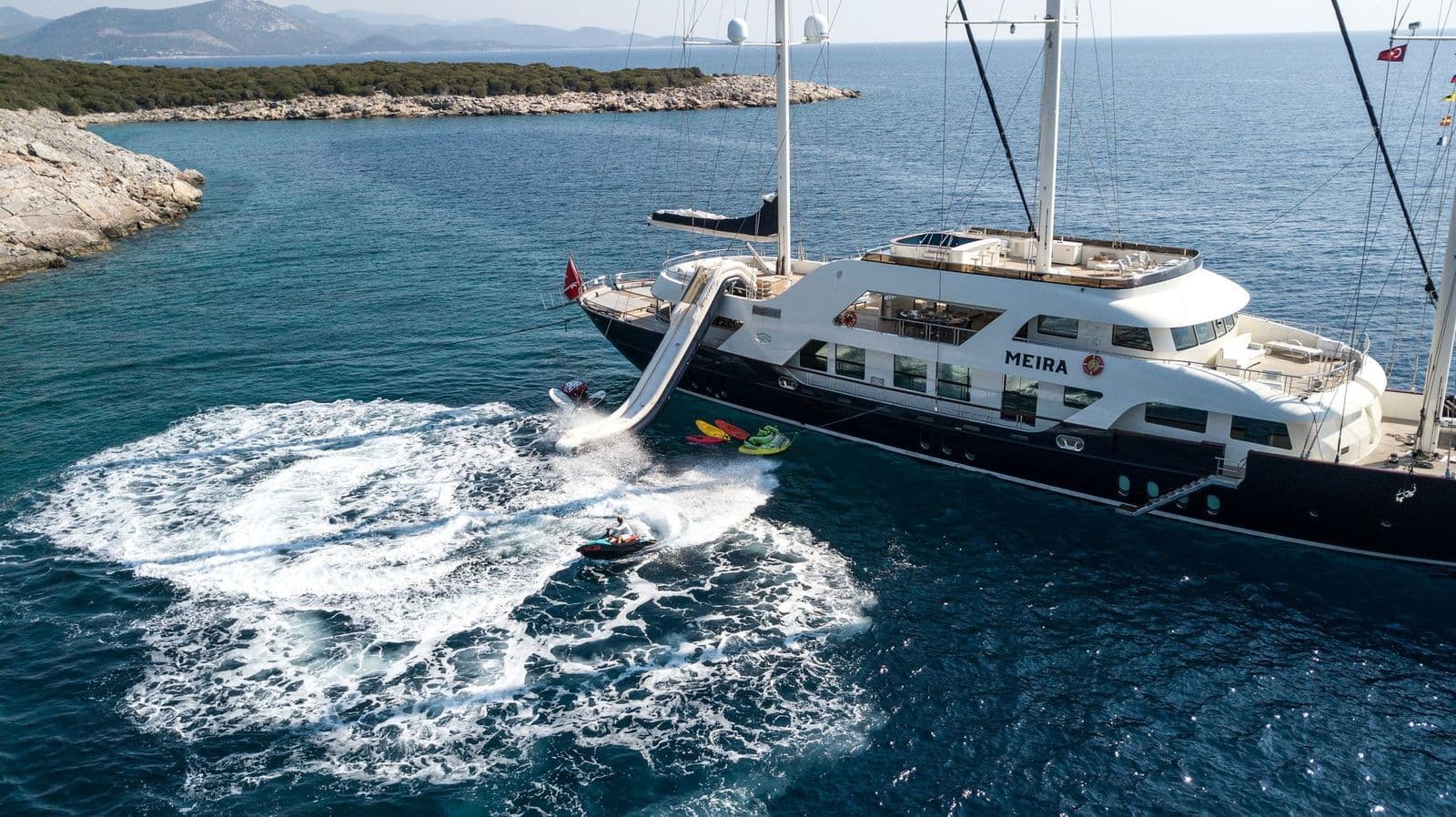 The wake of a jet ski beside M/S MEIRA at anchor in a bay