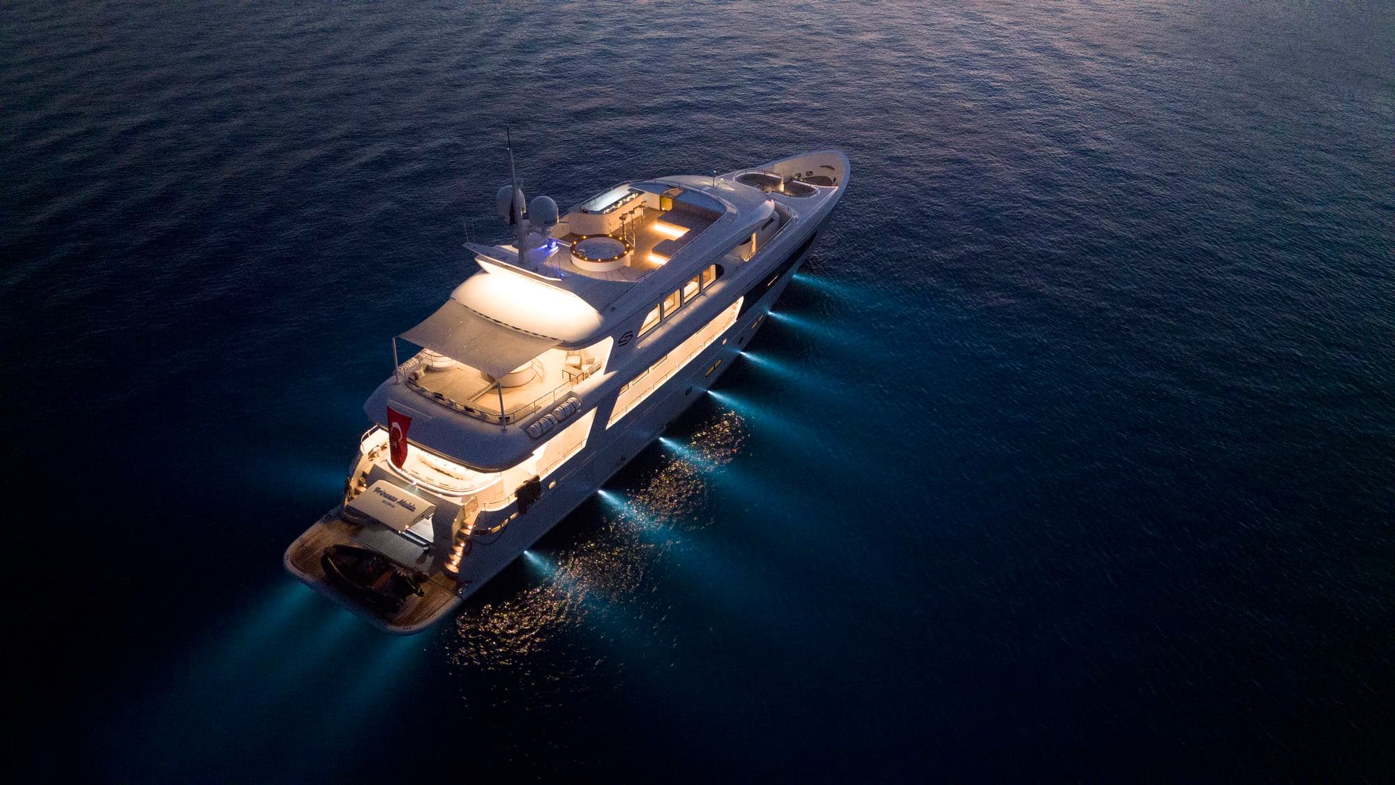 M/Y PRINCESS MELDA with her lights on at dusk, from the air