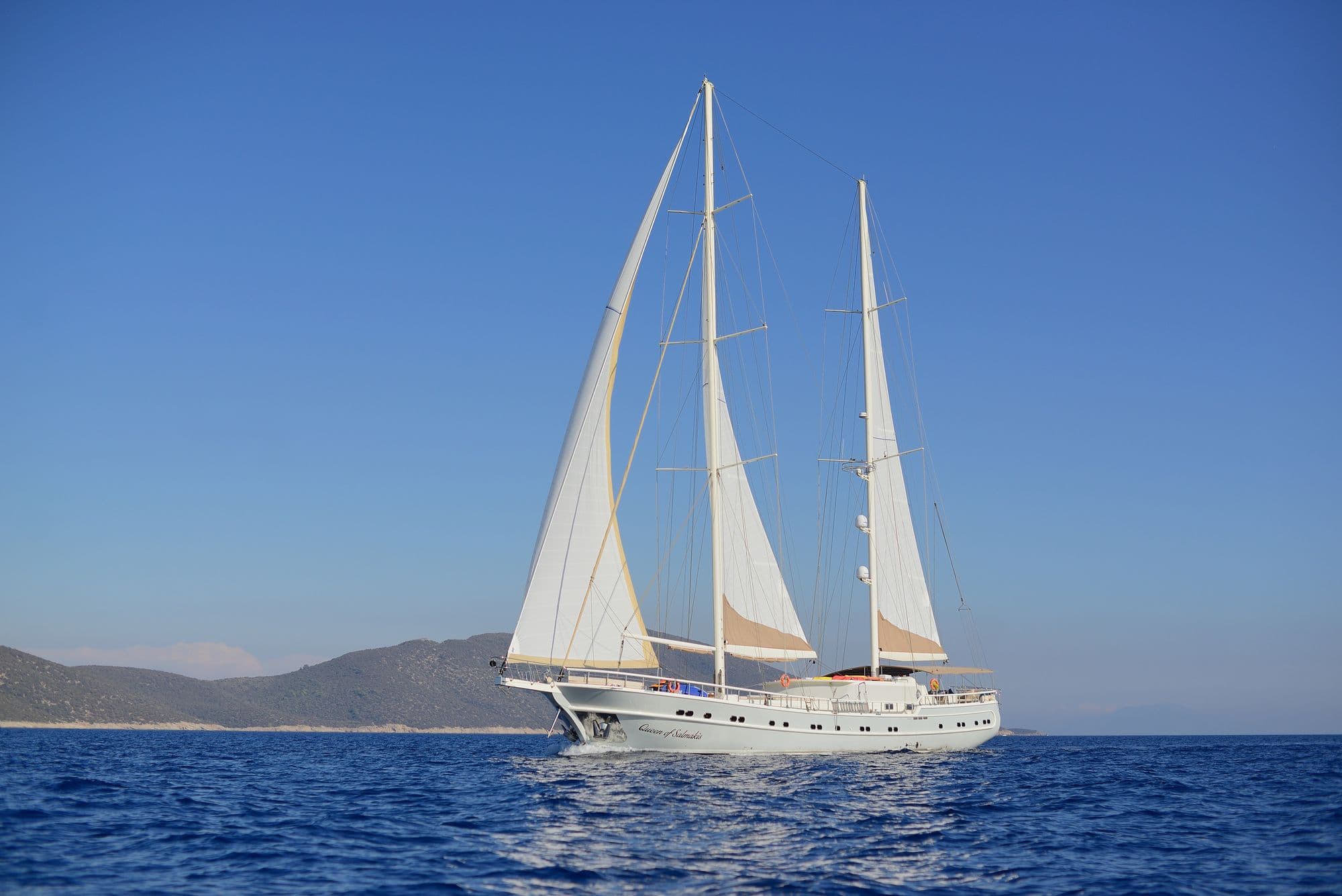 Queen of Salmakis with her sails set, off the coast